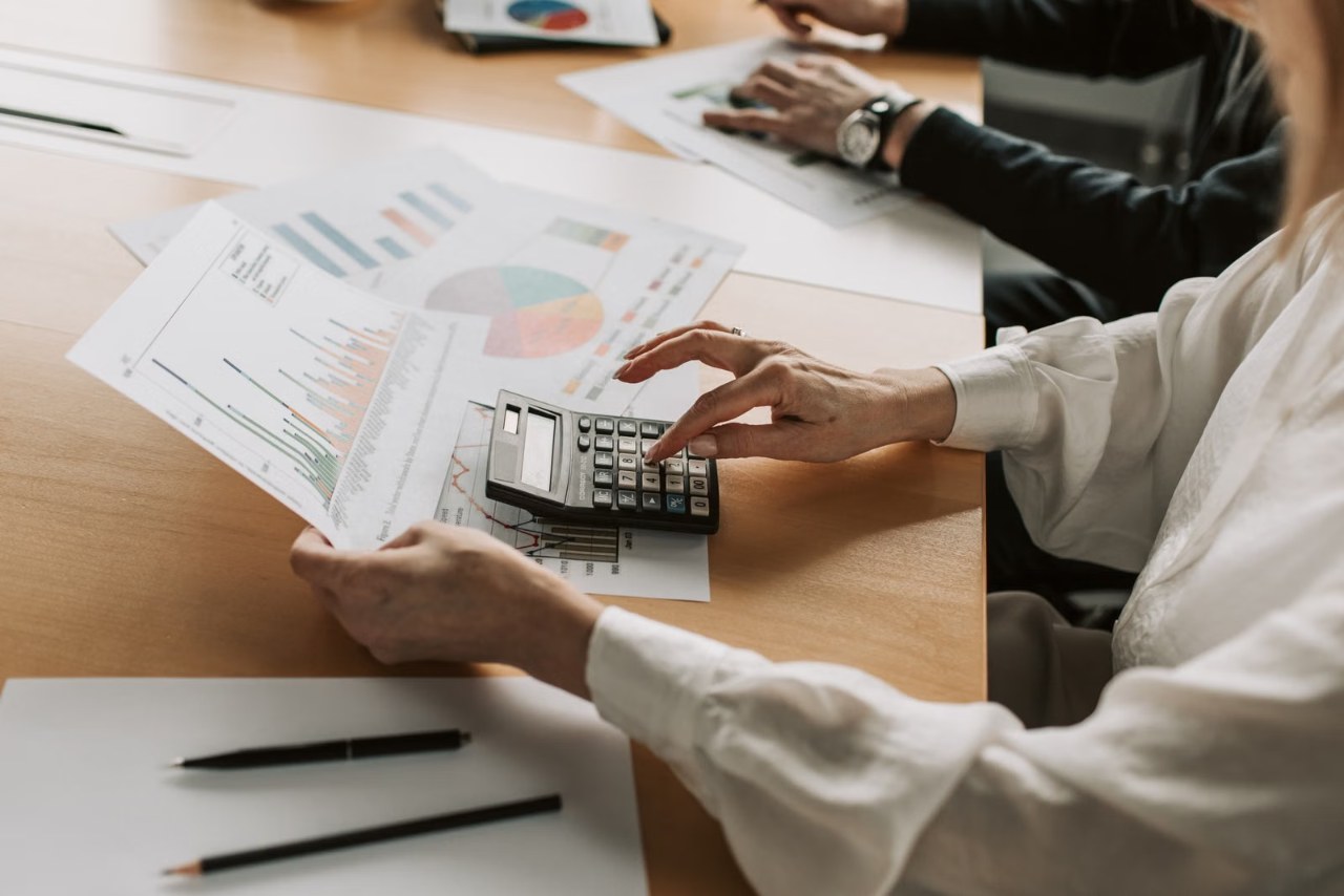 Mãos conferem demonstrativo financeiro com calculadora sobre a mesa